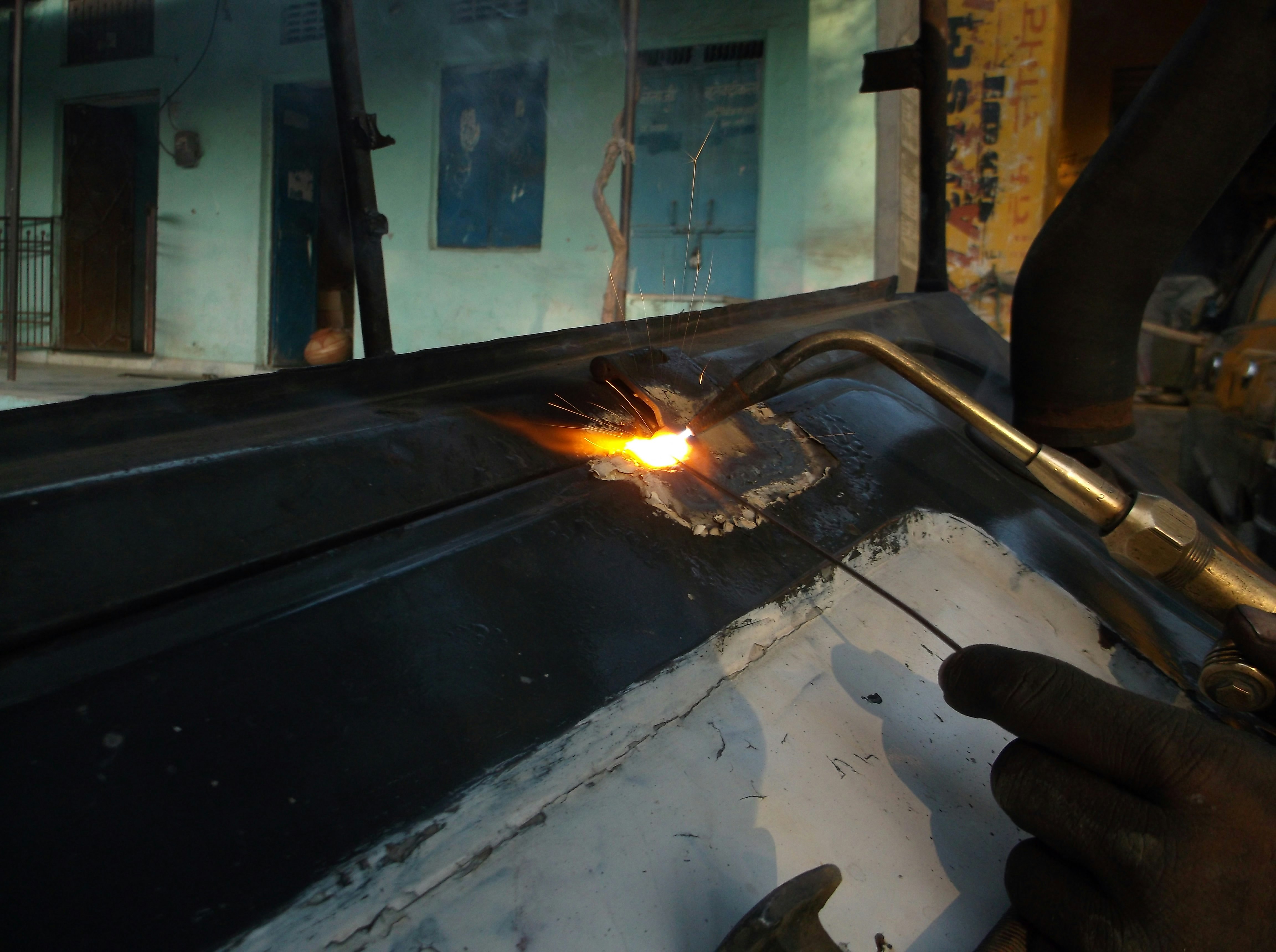 person welding black metal part